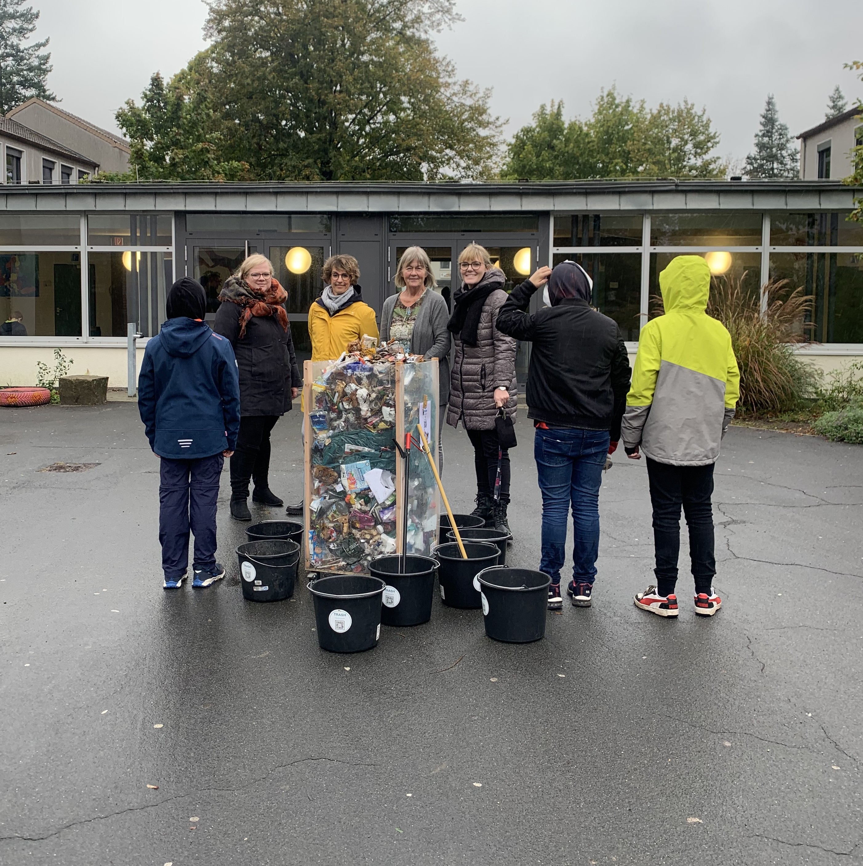 Müllbehälter vor Lehrerinnen und Schülern